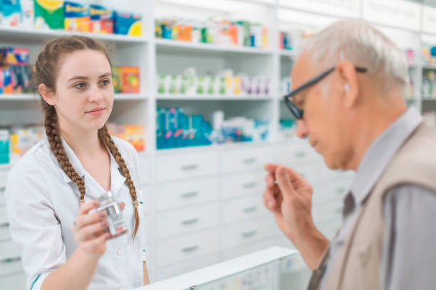 female pharmacist showing a can of medicine to an elderly male buyer - två burkar piller bildbanksfoton och bilder