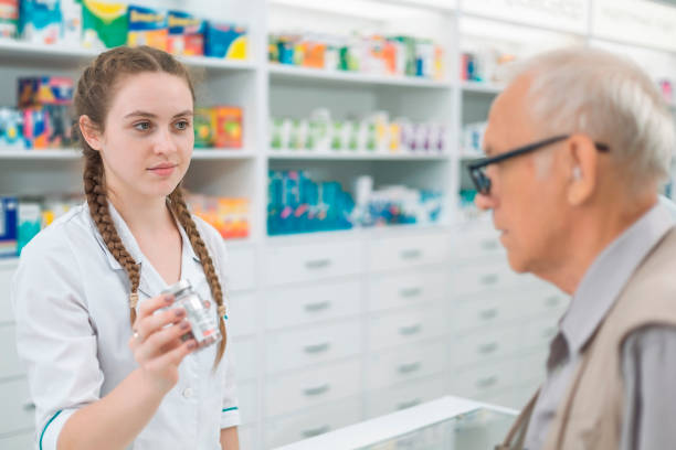 female pharmacist showing a can of medicine to an elderly male buyer - två burkar piller bildbanksfoton och bilder