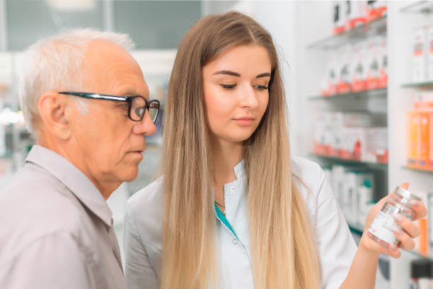 female pharmacist showing a jar of medicine to an elderly male buyer - två burkar piller bildbanksfoton och bilder