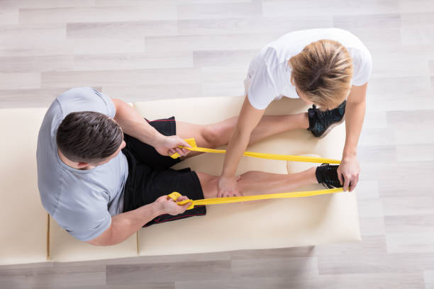 Female Physiotherapist Giving Exercise Treatment Elevated View Of A Female Physiotherapist Giving Exercise Treatment To Man physical therapy stock pictures, royalty-free photos & images