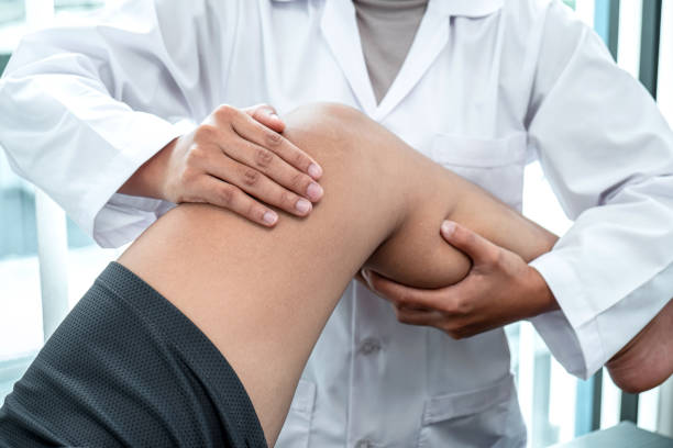 Female Physiotherapist working examining treating injured leg of patient, Doing exercises the Rehabilitation therapy pain his in clinic stock photo