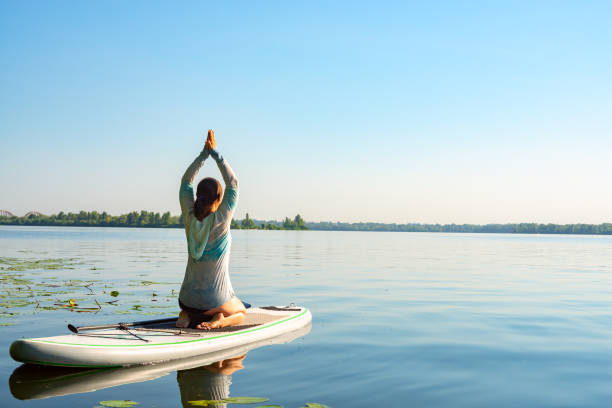 Female practicing yoga on a SUP board stock photo