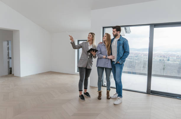 Female real estate agent showing an apartment for sale to a young couple Beautiful young couple buying an apartment with a help of a real estate agent. condition stock pictures, royalty-free photos & images