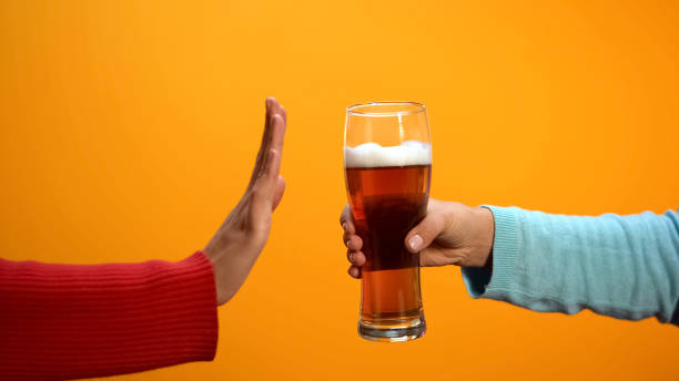 Female rejecting beer glass showing stop gesture, bad habit refusal, health care stock photo