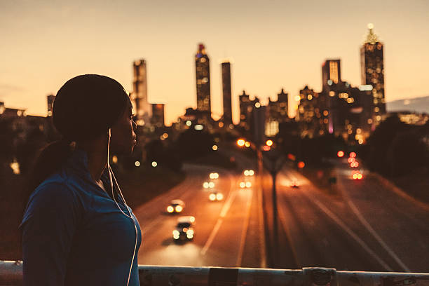 female runner looking out to the skyline Women jogger wearing earbuds and stopping to take a look a the skyline. atlanta stock pictures, royalty-free photos & images