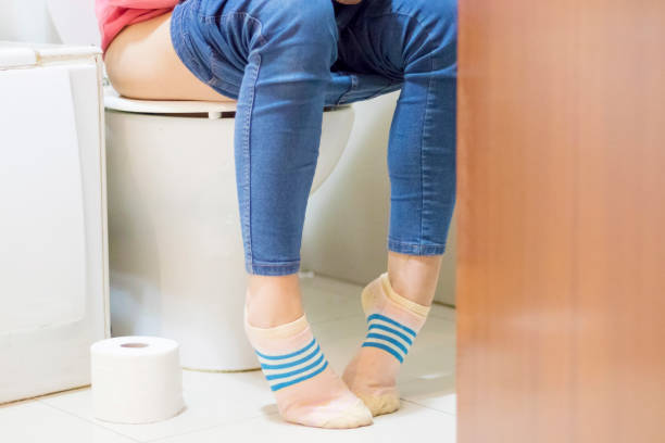Female setting at a toilet with her pants down stock photo