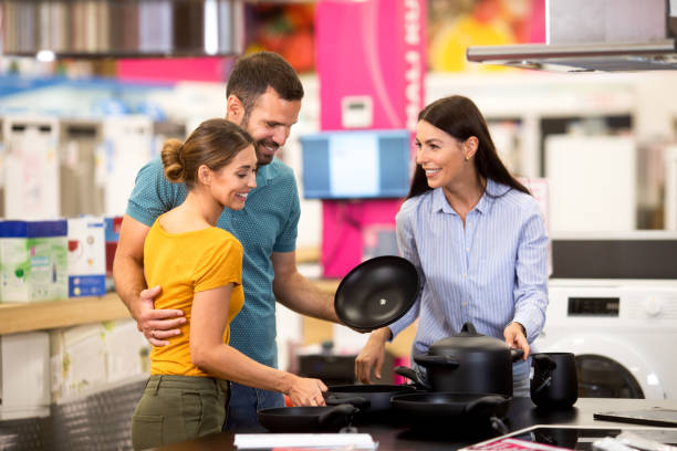 Female shop assistant shows dishes to a young couple stock photo