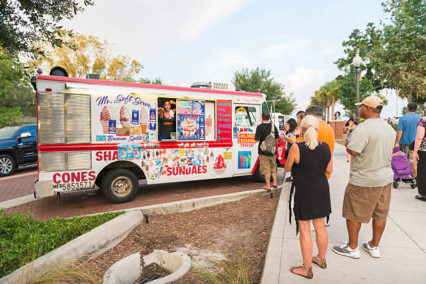 Female Small Business Owner Sells Ice Cream From Truck Kissimmee Kissimmee, United States - August 20, 2016: On a Saturday afternoon at the Kissimmee Lakefront park a woman runs a small business from a parked ice cream truck. People look to see what sweets she is selling. ice cream truck stock pictures, royalty-free photos & images