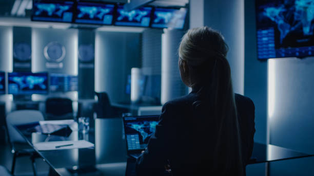 специальный агент-женщина работает на ноутбуке в фоновом режиме специальный агент в заряда переговоры с военным человеком в комнате монит� - fbi стоковые фото и изображения