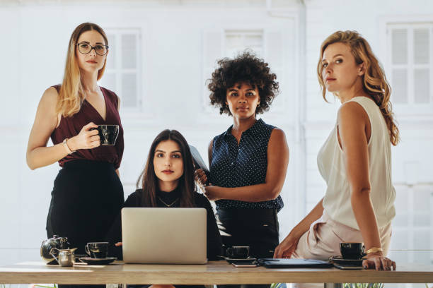 Female startup business team Group of multiracial businesswomen in casuals together at office desk and looking at camera. Female startup business team portrait. staring stock pictures, royalty-free photos & images