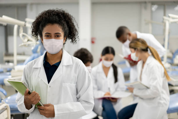Female student back at school and wearing a facemask during the pandemic Portrait of a Female student back at school and wearing a facemask during the COVID-19 pandemic while looking at the camera medical student stock pictures, royalty-free photos & images