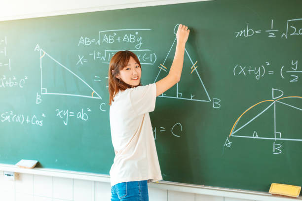 female student in the classroom writing on chalkboard mathematical equations female student in the classroom writing on chalkboard mathematical equations maths stock pictures, royalty-free photos & images