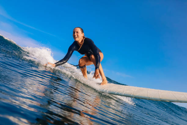 female surfer on a blue wave - surf imagens e fotografias de stock