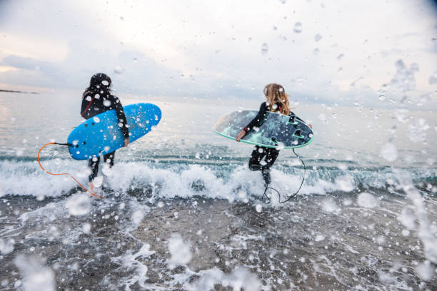 Female Surfers With Boards Running Into Water stock photo