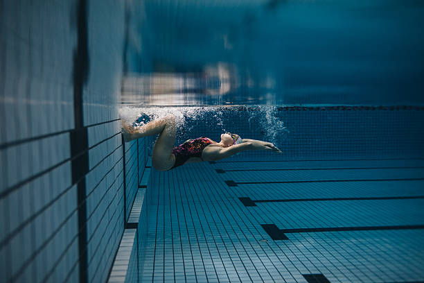 Female swimmer in action inside swimming pool Shot of fit young woman turning over underwater. Female swimmer in action inside swimming pool. jacob ammentorp lund stock pictures, royalty-free photos & images