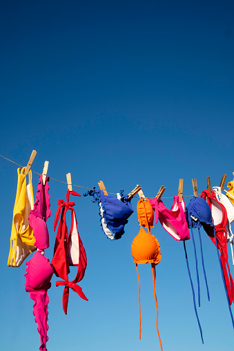 Series of female swimwear of various colors hanging in the sun to dry in the summer season