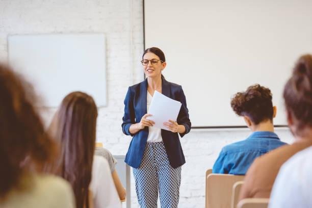 Female teacher explaining students in classroom stock photo