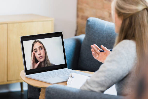 Female therapist meets with patient via video conferencing stock photo