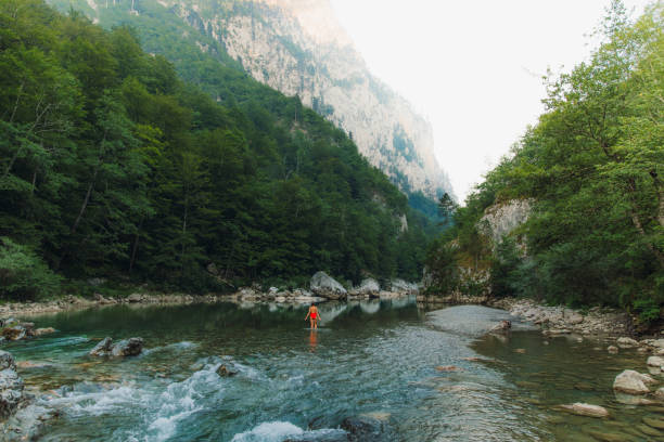 Female traveler refreshing in the river inside the scenic mountain canyon in Montenegro Young woman in red swimsuit exploring the Balkans, enjoying summer sunset in the canyon with mountain view at Durmitor National park women in skimpy bathing suits stock pictures, royalty-free photos & images