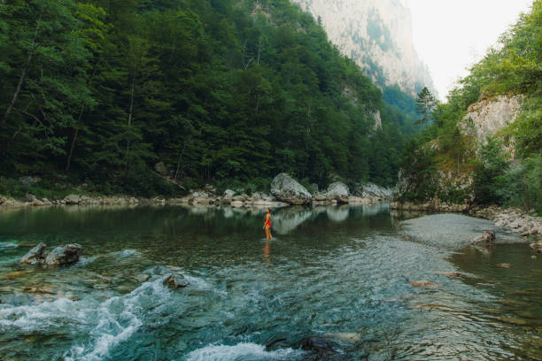Female traveler refreshing in the river inside the scenic mountain canyon in Montenegro Young woman in red swimsuit exploring the Balkans, enjoying summer sunset in the canyon with mountain view at Durmitor National park women in skimpy bathing suits stock pictures, royalty-free photos & images