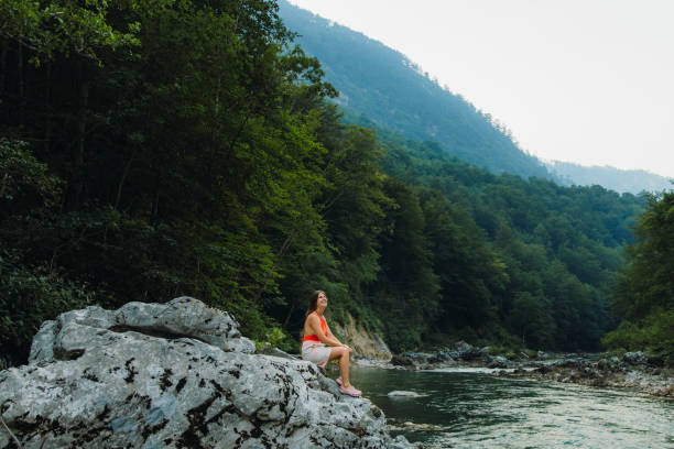 Female traveler sitting on the rock inside the scenic mountain canyon in Montenegro Young woman in red swimsuit exploring the Balkans, enjoying summer sunset in the canyon with mountain view at Durmitor National park women in skimpy bathing suits stock pictures, royalty-free photos & images