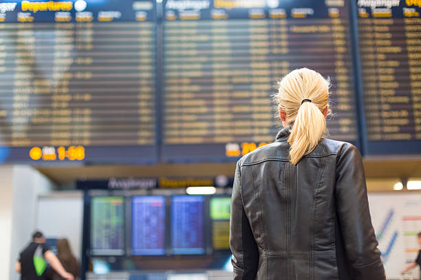 Female traveller checking flight departures board. stock photo