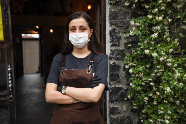 официант-женщина с защитной маской перед кафе - small business saturday стоковые фото и изображения