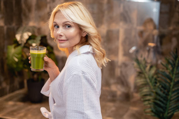 Female with a glass of vegetable beverage Portrait of an attractive woman drinking a green smoothie drinking smoothie stock pictures, royalty-free photos & images