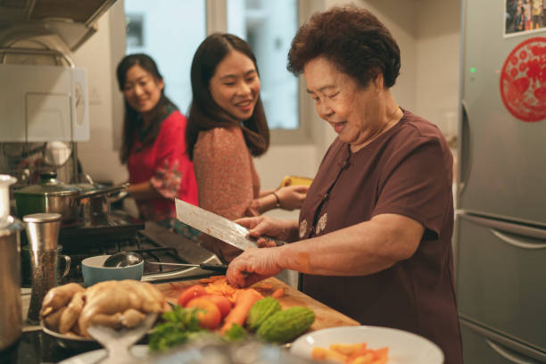Females from a multi-generation Asian family in a kitchen during the preparation of reunion dinner stock photo