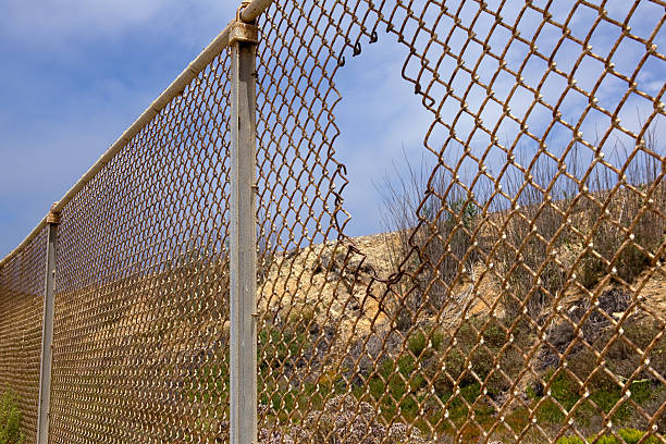 Fence with hole Fence with hole in California desert. rusty fence stock pictures, royalty-free photos & images