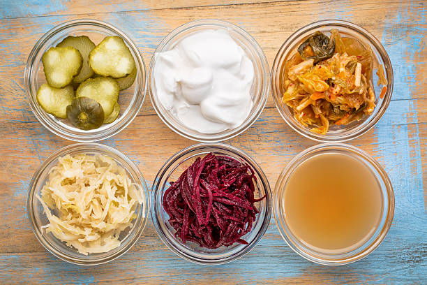 fermented food collection a set of fermented food great for gut health - top view of glass bowls against grunge wood:  cucumber pickles,  coconut milk yogurt, kimchi, sauerkraut, red beets, apple cider vinegar fermenting stock pictures, royalty-free photos & images