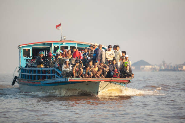 A Ferry is carrying crowded people and their motorbikes to crossing a river stock photo