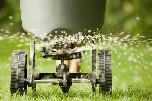 fertilizer pellets spraying from spreader - gazon stockfoto's en -beelden