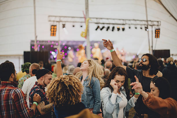 Festival fun Group of friends dancing together in a marquee at an outdoor music festival. music festival stock pictures, royalty-free photos & images