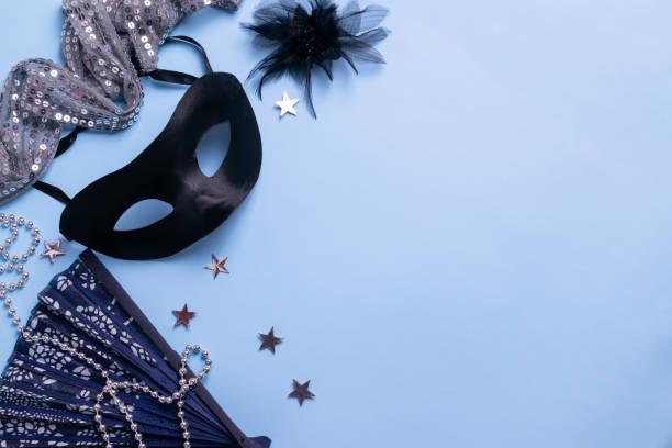festive carnival accessories, mask, elegant fan and jewelry on blue pastel background. flat lay with copy space - carnival accessories flat lay imagens e fotografias de stock