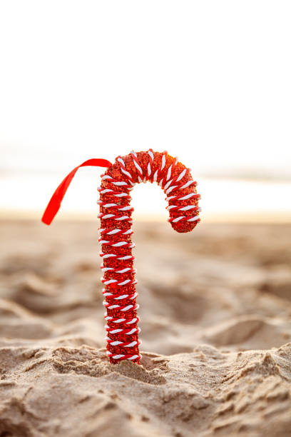 Festive Christmas red candy cane on sandy beach at sunset in California stock photo
