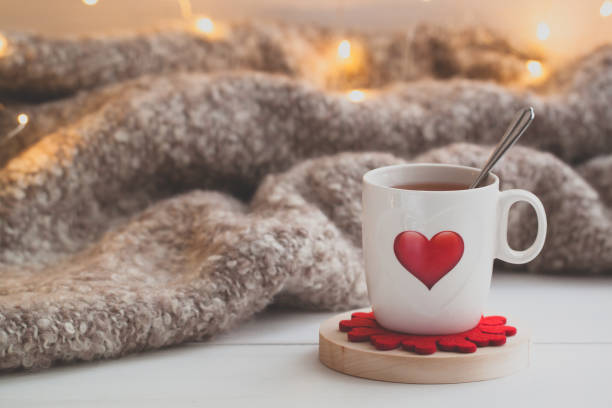Festive Cup of tea with a smoke and a red heart over the knitted plaid Festive Cup of tea with a smoke and a red heart over the knitted plaid. Toned february stock pictures, royalty-free photos & images