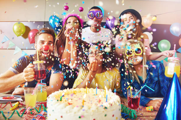 Festive partygoers surrounded by confetti Group of six male and female festive partygoers in front of large white frosting covered cake surrounded by confetti in room happy birthday in danish stock pictures, royalty-free photos & images