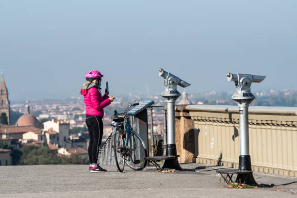 Few Florentines and no tourists on the belvedere at Piazzale Michelangiolo in Florence. Florence, Italy - Nov 9, 2020: Telescopes pointing at the city are without tourists in an unusually and absurdly empty Piazzale Michelangelo during the Covid 19 lockdown in Florence. arno river stock pictures, royalty-free photos & images