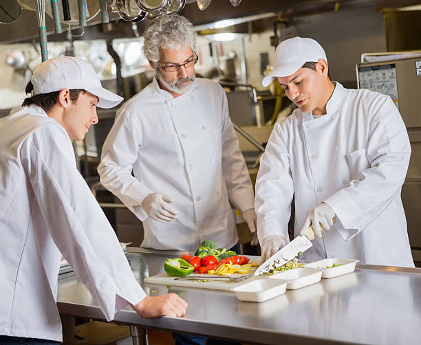 Kulinaarinen koulu tunkeilija opettaa oppilaita kaupallisessa keittiössä