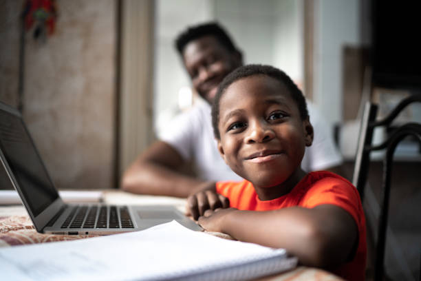Muotokuva isästä ja pojasta, jotka opiskelevat kannettavalla tietokoneella online-luokalla kotona