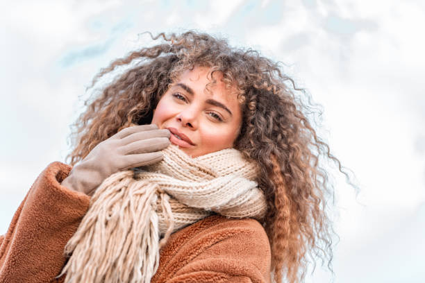 Portrait of a beautiful young woman with big curly hair, wearing warm clothes outdoors in wintertime.
