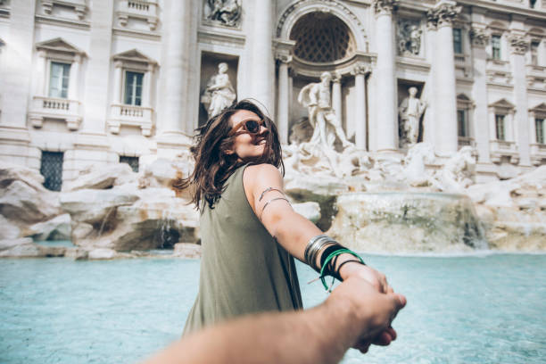 Young woman taking follow me picture in front of Trevi fountain in Rome