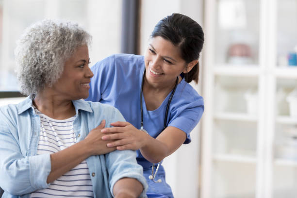 Caring nurse smiles at an African American senior female patient.