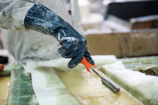 Fiberglass factory worker rolls solution through fibreglass sheets fiberglass factory worker rolls solution through fiberglass sheets with a roller fibreglass stock pictures, royalty-free photos & images