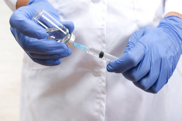 Fight against covid-19, doctor holding syringe and vial with vaccine, children and teens vaccination concept stock photo