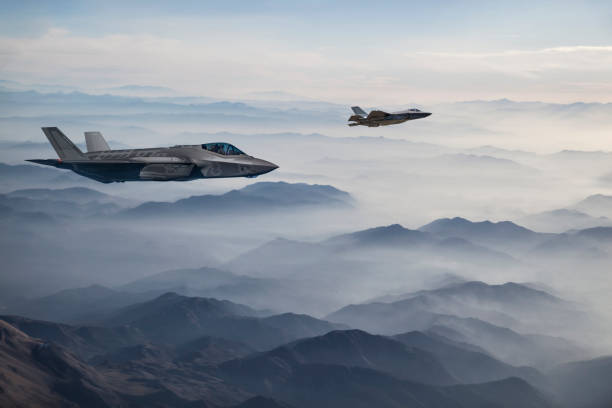 fighter jets flying over mountains at dusk - f 35 imagens e fotografias de stock