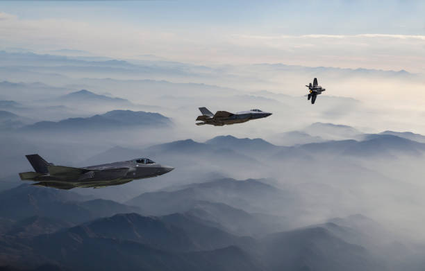 fighter jets flying over the misty mountains at dusk - f 35 imagens e fotografias de stock