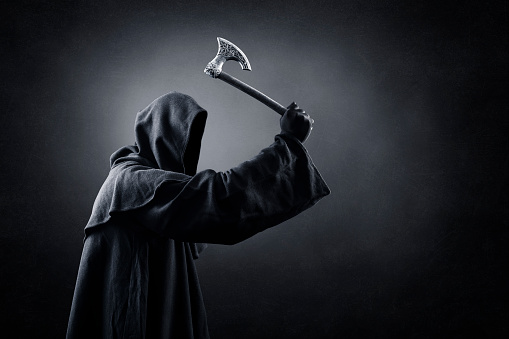 Figure in hooded cloak with axe in the dark