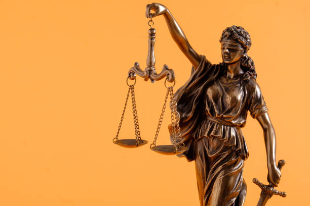Figure of justice holding scales over orange stock photo
